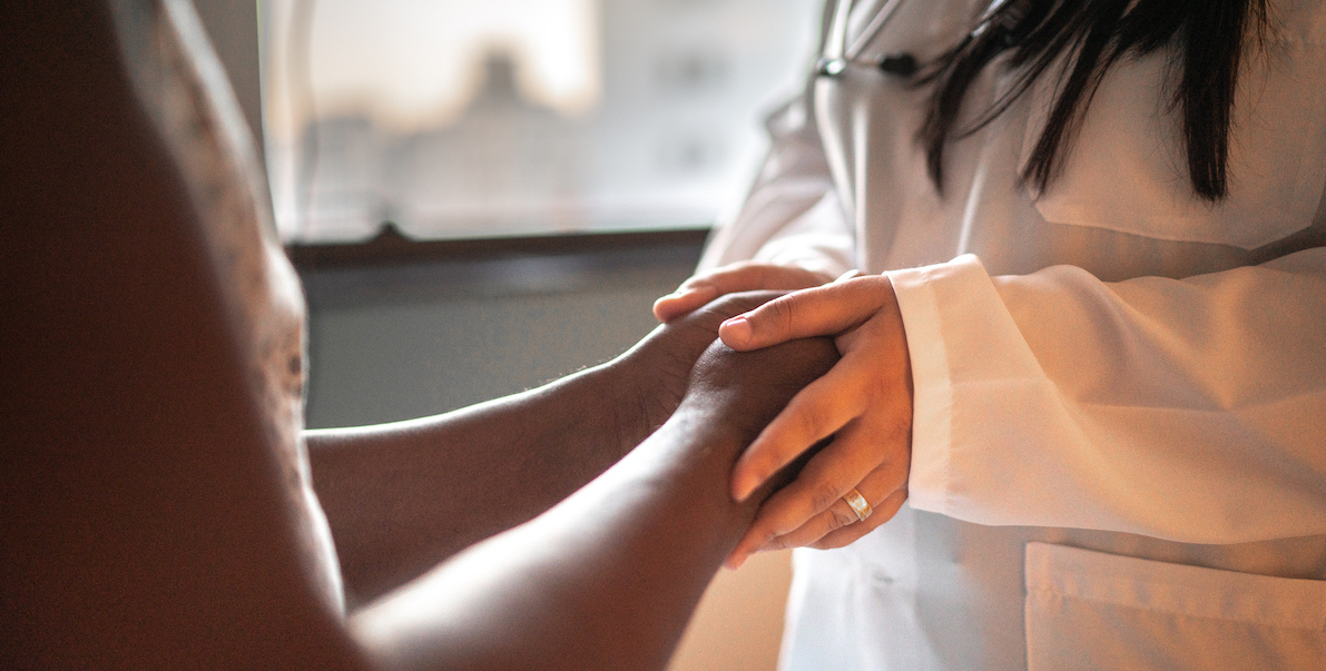 Female doctor holding hands of her patient at hospital room