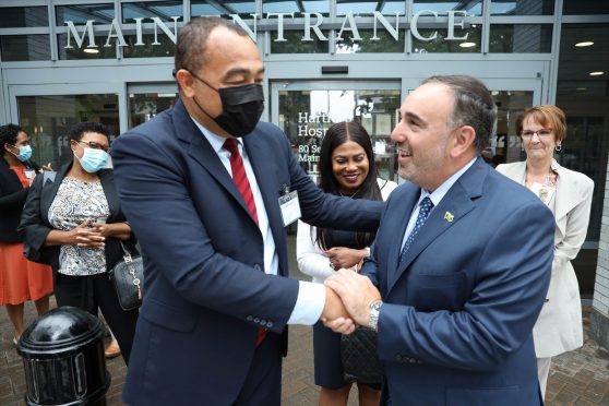 Two healthcare experts shake hands in front of Hartford Hospital.