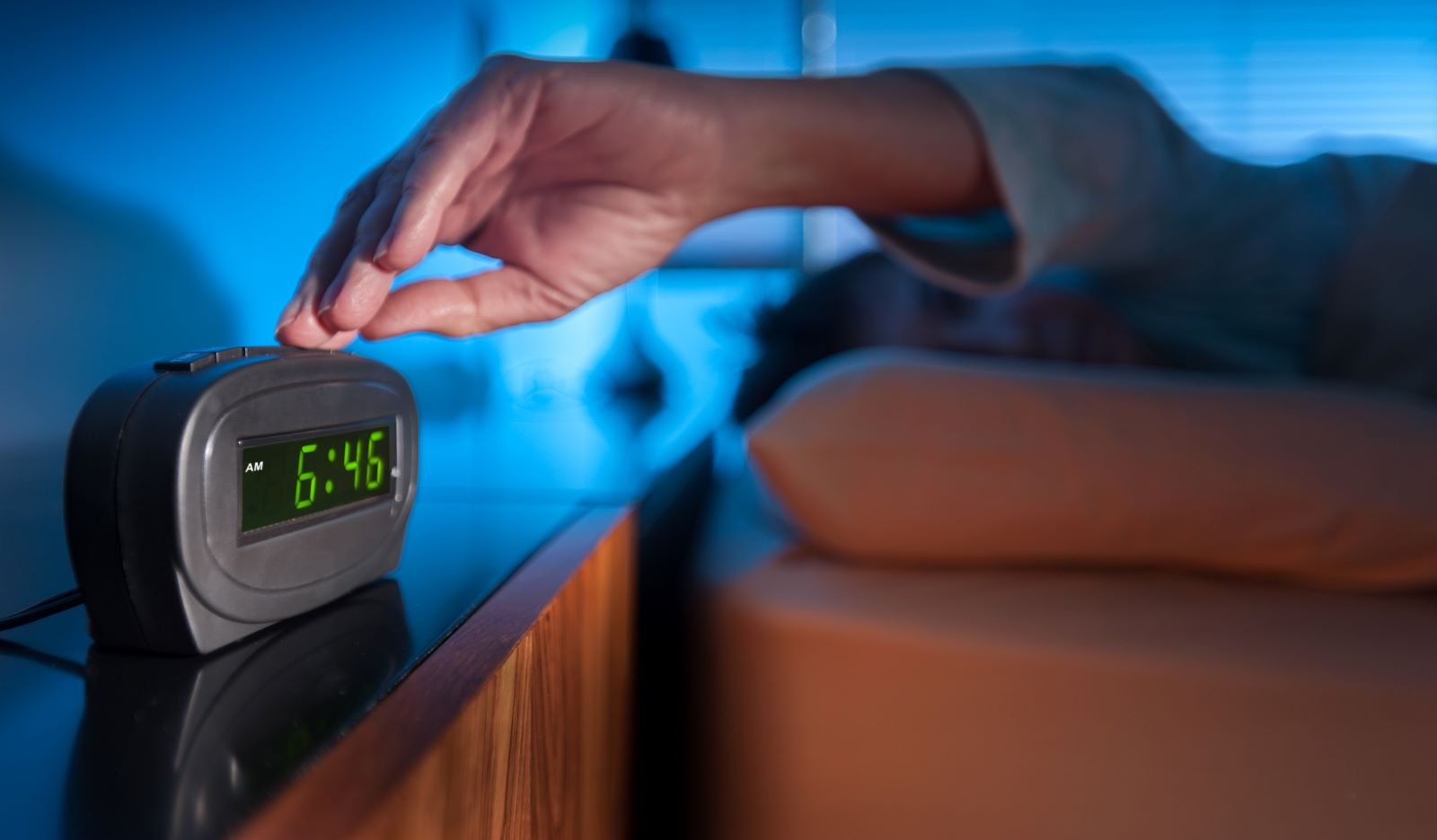 A person hitting the snooze button on their alarm.