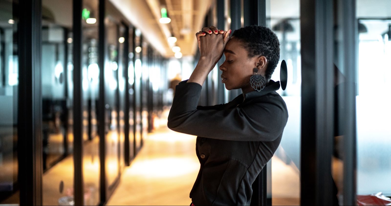 Woman clasps her hands and appears stressed out at work.