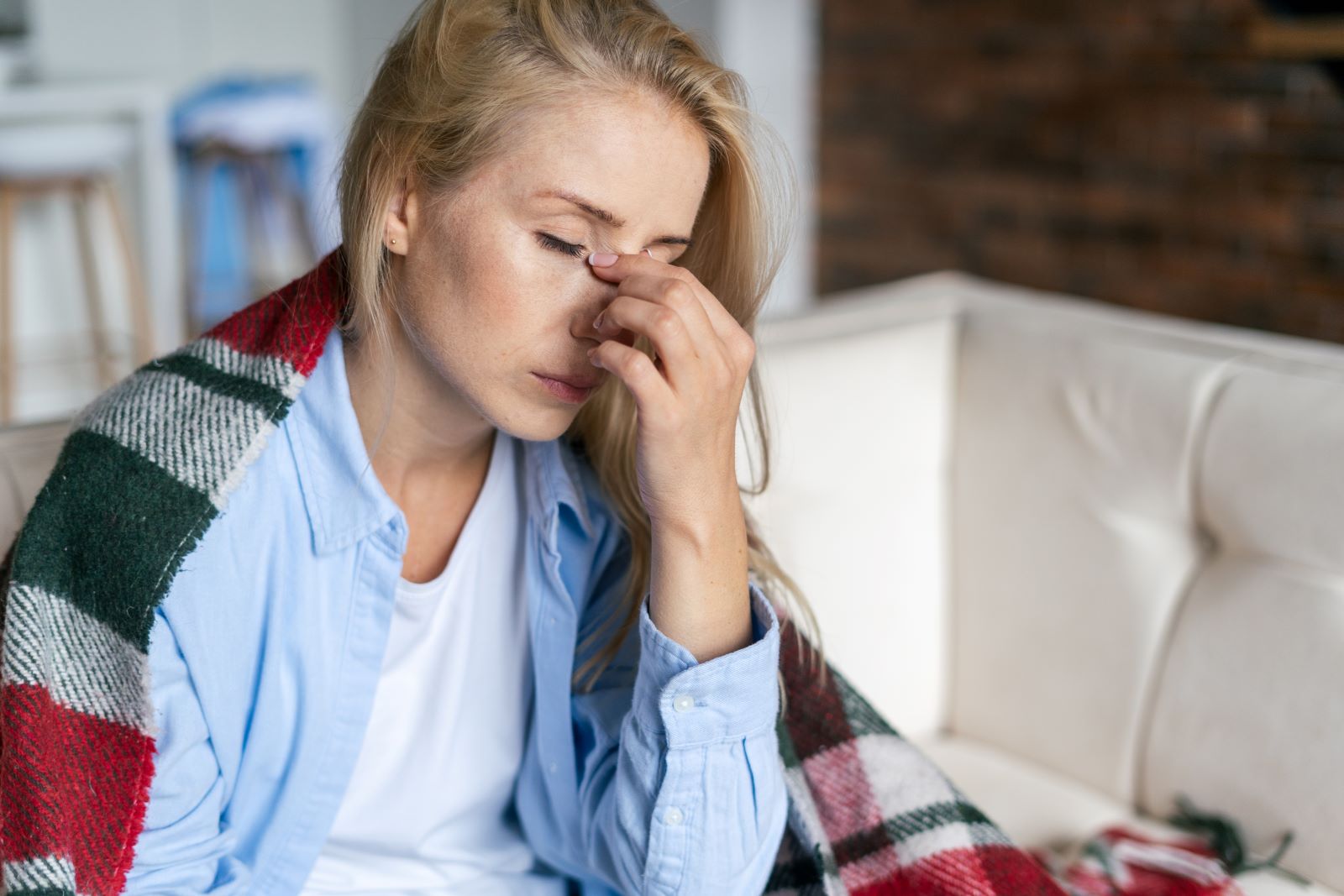 Tired, stressed woman touches the bridge of her nose.