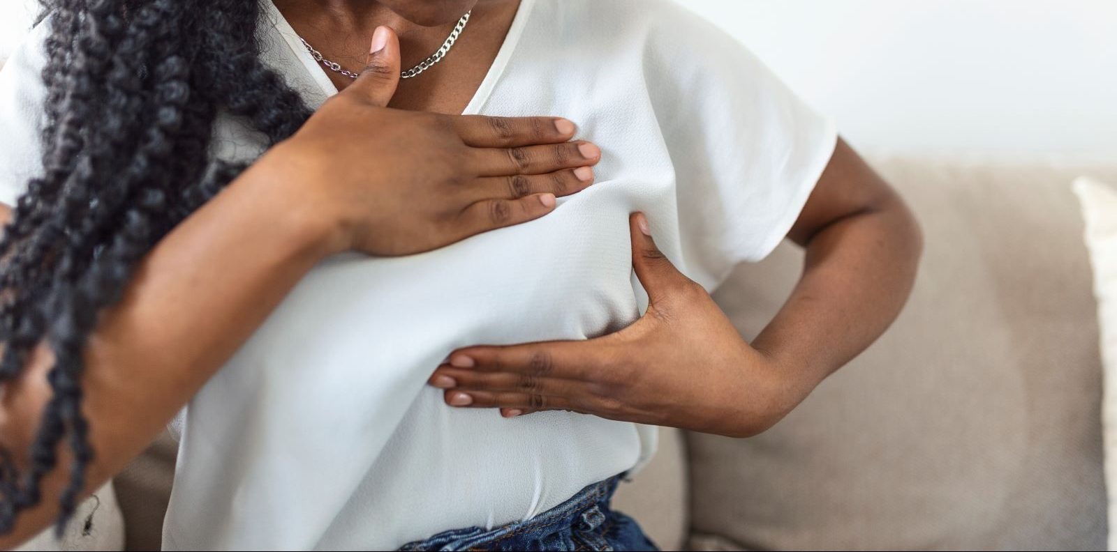 A woman performs a breast exam on herself.